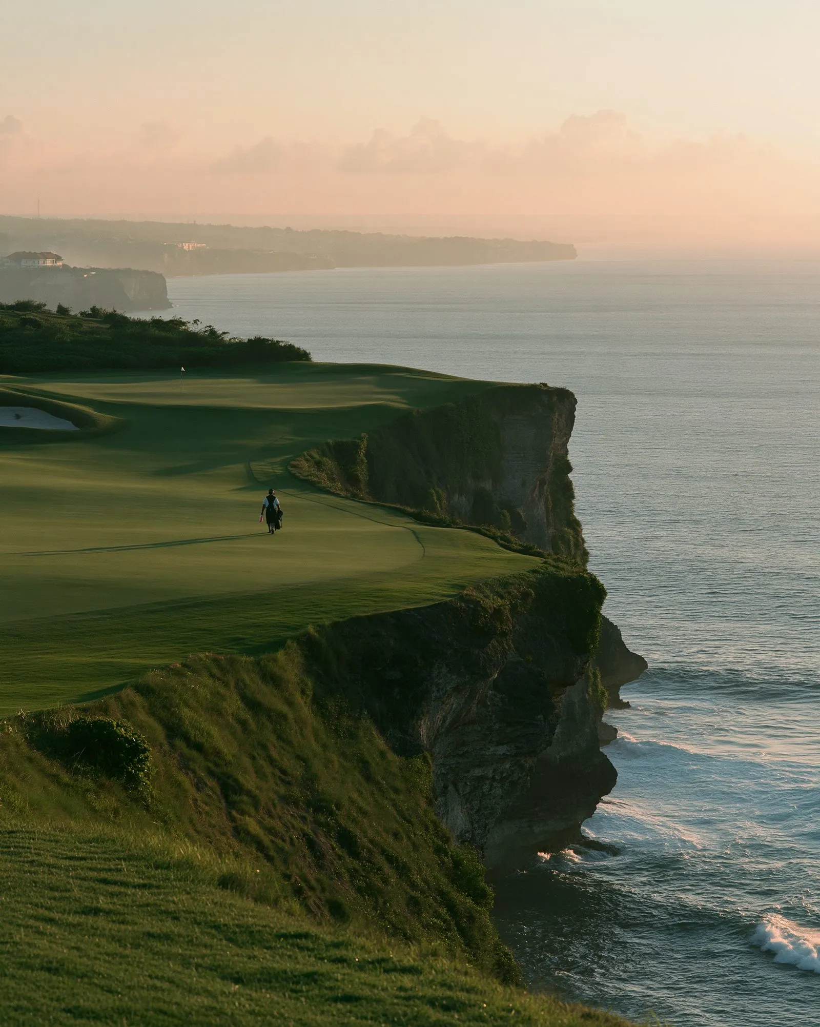 A clifftop fairway above the Indian Ocean in Bali, late afternoon light